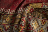 Distressed Anatolian rug's textural pile with cherry red, saffron, and brown geometric patterns.