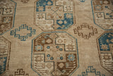 Vintage distressed Ersari carpet detail showing repeating guls in sand, brown, and dusty blue.