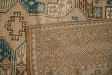 Distressed Ersari carpet folded, showing geometric pattern and foundation weave in sand, brown, dusty blue.