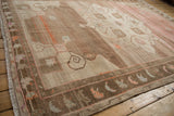 Distressed Kars carpet corner with serrated leaf border, abrashed field, pale fuchsia tendrils.