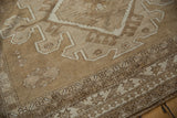 Vintage Oushak rug corner with geometric medallion, faded floral field, and pawn motif border.