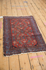 Malayer rug corner with cherry red Herati motif, blue Serbend border, and tattered edge detail.