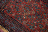 Close-up of vintage Persian Malayer rug: cherry red Herati pattern, sapphire motifs, and knot head wear.