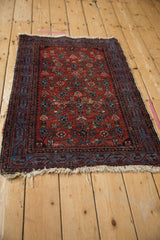 Worn corner of Malayer rug, featuring blue Serbend border, red Herati field, and tattered white fringes.