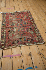 Vintage Lilihan rug's lower corner, showing faded raspberry field, wear, and tattered fringe.