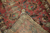 Folded corner of vintage Lilihan rug, showing worn raspberry field with foundation and detailed woven reverse.