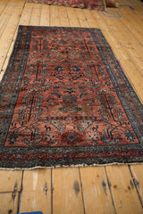 Corner of vintage Persian Hamadan rug: dusty red field, blue serrated leaves and fringe.