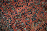 Expressive contoured serrated leaves and blossoms in blue and copper on dusty red pile.