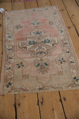 Vintage distressed Oushak rug showing central stepped medallion, finned design, and muted blush and teal.
