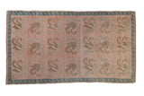 Vintage distressed Oushak rug with rows of floral tendrils in muted silver and beige on a dusty rose field with a turquoise blue border.