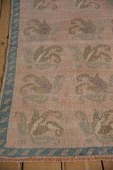 Low, evenly worn pile of a vintage Turkish Oushak rug in dusty rose and pale turquoise.