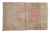 Vintage distressed Oushak rug featuring a prayer arch design in soft pink, cream, and dusty green.