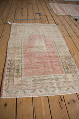 Angled view of a vintage distressed Oushak rug, showing the full prayer design motif.