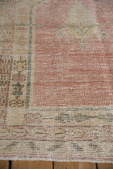 Low pile and visible knot heads on a distressed Turkish Oushak in dusty pink and sea foam green.