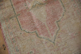 Worn, low-pile texture showing visible knot heads on a pink and cream palmette.