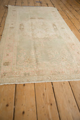 Distressed vintage Oushak runner pile showing evenly worn pale green and rose motifs.