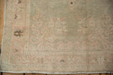 Distressed Oushak rug corner, showing fringe, worn pile, pale green, rose, and ivory.