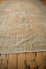 Vintage distressed Oushak carpet with worn pile, foundation showing through, and muted pastel tones.