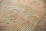 Distressed vintage Oushak carpet with worn pile, revealing foundation and muted peach tones.