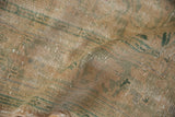 Textured close-up of distressed vintage Oushak rug, worn peach and green pile over foundation.