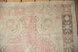 Distressed Oushak rug with faded pale pink, beige, and geometric charcoal brown border.
