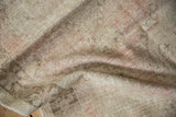 Textured pile showing distressed areas in soft beige, pale pink, and charcoal.