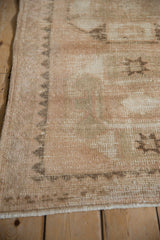 Distressed Kurd rug with worn pile, geometric chevron border, and visible foundation in beige and rose.