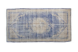 Vintage Distressed Oushak rug in cobalt blue, cream, medallion, and seeded spandrels.