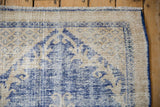 Worn pile texture of vintage distressed Oushak rug, with cobalt blue side cord.