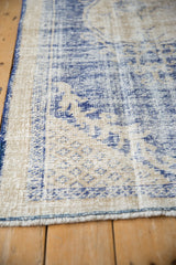 Textured detail of distressed vintage Oushak rug with worn cobalt blue motifs and cream foundation.