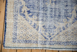 Vintage distressed Oushak rug corner with worn cobalt blue pattern, cream pile, and blue selvage.