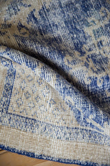Vintage Oushak rug with distressed texture; worn cobalt blue and cream pile revealing foundation.