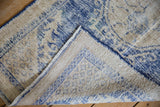 Vintage distressed Oushak rug showing wear to foundation, knot heads, and intact selvage.