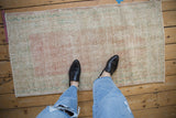 Distressed vintage Oushak rug featuring faded rose, ivory, and pale green tones.