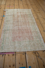 Distressed vintage Oushak rug with exposed foundation and muted rose, mint tones.