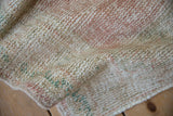 Distressed vintage Oushak rug pile, showing soft ivory, dusty rose, pale mint green hues.