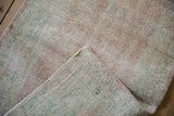 Distressed Oushak rug pile texture, revealing wear to knot heads with dusty rose and mint.