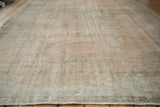 Low-angle view of the distressed Oushak carpet's textured, low pile and visible knot heads.