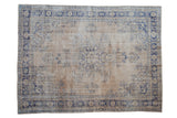 Distressed vintage Oushak rug, hand knotted, with faded cobalt floral patterns on a light field.