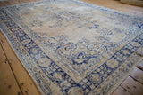 Worn texture and vibrant cobalt blue floral motifs on the distressed Oushak carpet.