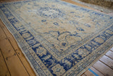 Decorative worn surface of vintage Oushak carpet with pale gold and cobalt blue curvilinear design.