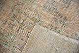 Distressed Oushak rug pile with beige, blue, and green, showing woven foundation.