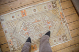 Distressed Oushak rug with ivory field, geometric medallion, tangerine, chocolate brown florals.