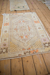 Distressed Oushak rug corner showing ivory field, tangerine geometric flower border, seeded spandrel.
