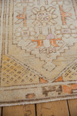 Distressed Turkish Oushak rug corner detail, geometric floral motifs in cream and tangerine.