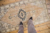 Distressed Oushak runner featuring a worn dusty gold field and navy charcoal medallion.