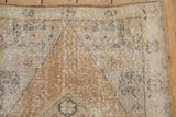 Distressed vintage Oushak rug corner with diamond spandrel, dusty gold and beige.