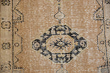 Distressed vintage Oushak rug detail: central motif with elongated finials, dusty gold and navy wear.
