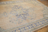 Low pile and knot heads visible on a distressed Oushak carpet with faded cobalt blue vinery.