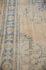 Detail of the distressed Oushak carpet's low-pile texture, showing the blue palmette border.